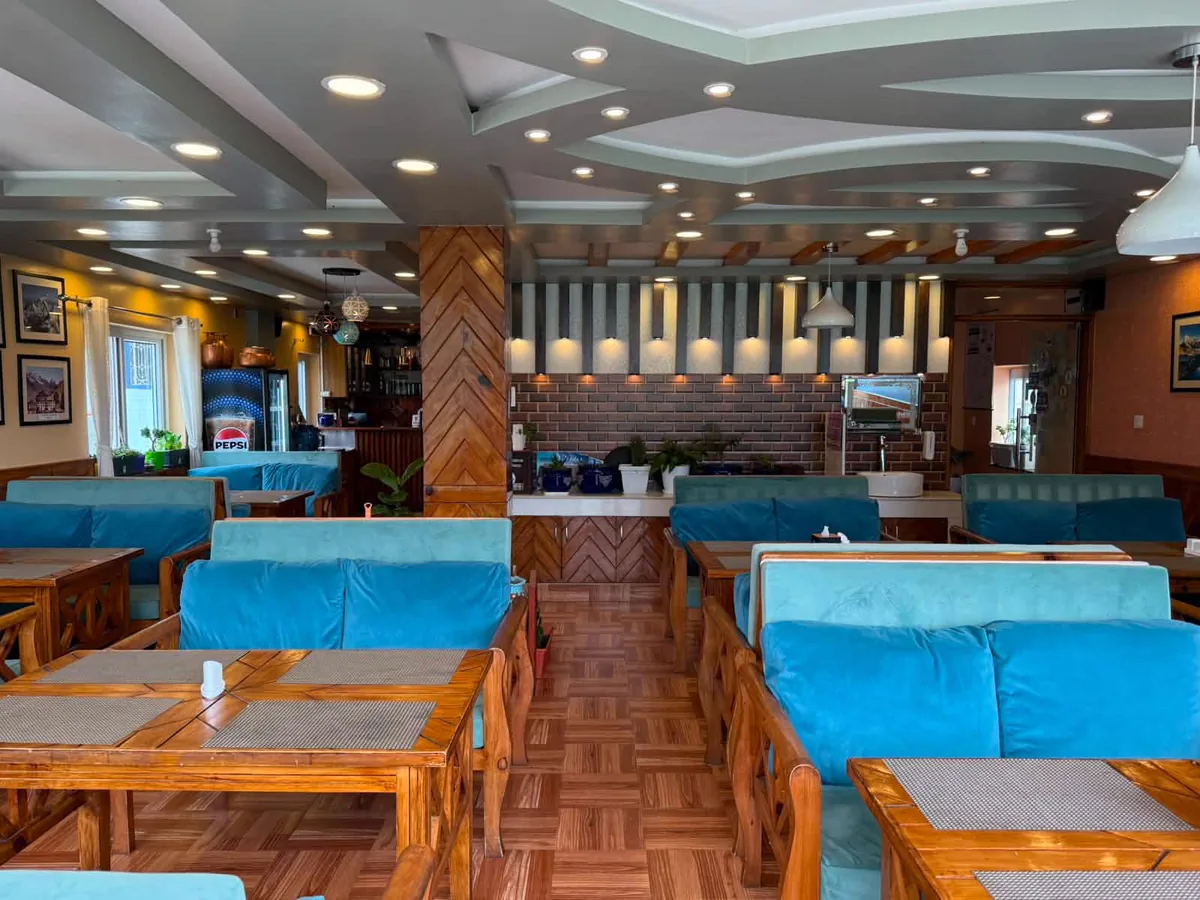Spacious hotel dining area with warm wood finishes and table seating